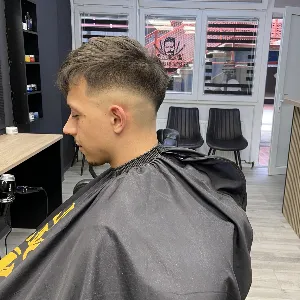 Vlasnica The Royal Barber Shopa u procesu šišanja muškarca srednje dobi sa mašinicom