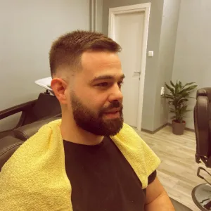 Mlađi klijent u ogledalu gleda svoju novu fade frizuru
